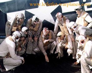 Commanding Officer, Lieutenant Commander Paul D. Buie, (center) briefs his pilots for an upcoming mission, during the Gilberts operation, November-December 1943. An F6F-3 Hellcat fighter is behind them. Note flight gear, markings on helmets and life vests. [US Navy]